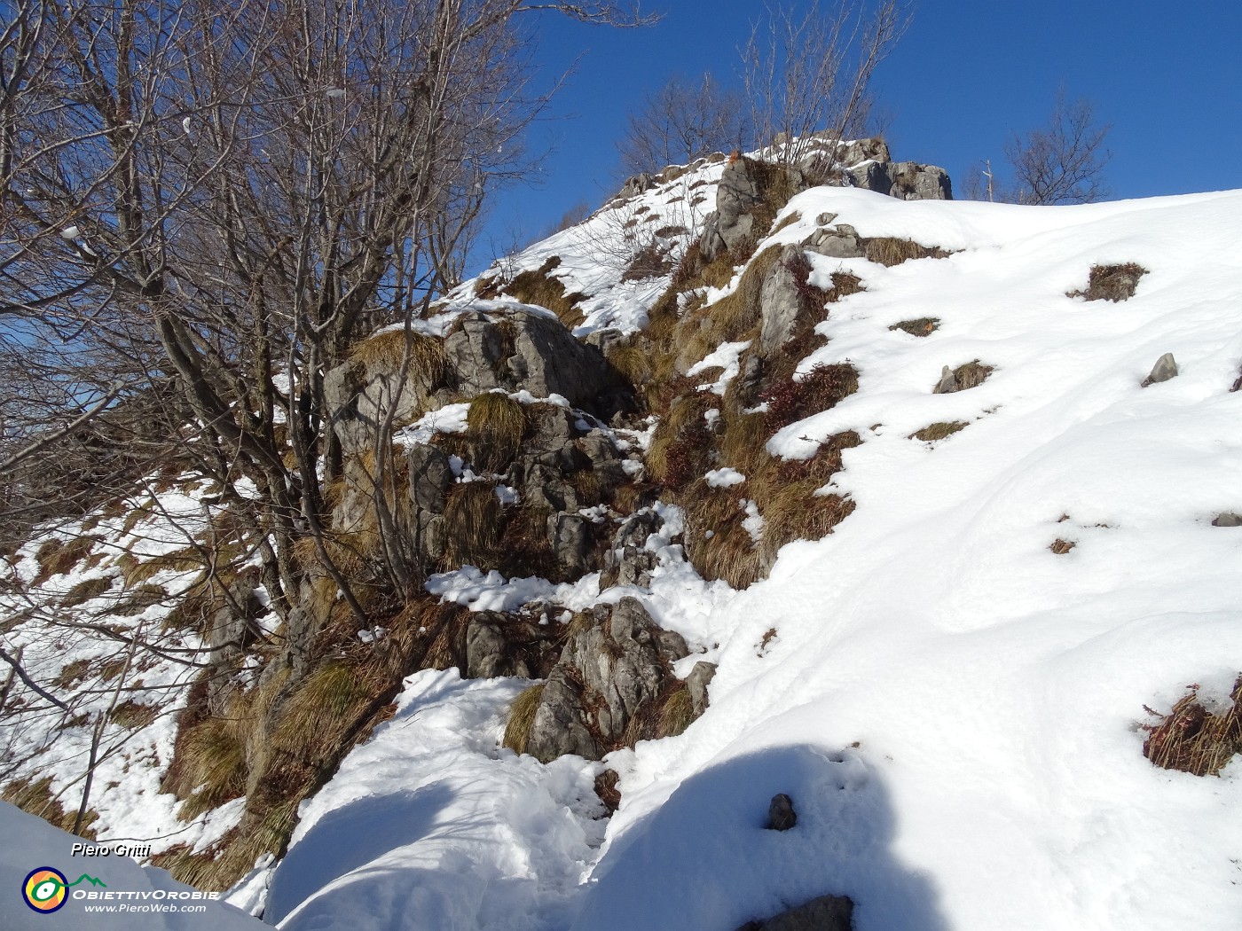 52 In decisa ripida salita anche su facili roccette pestando neve rammollita.JPG